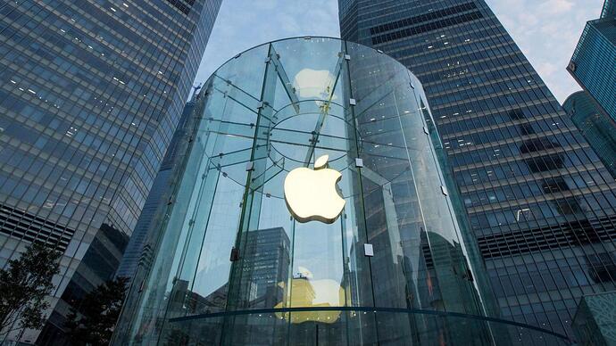 The apple logo on a clear round store is visible in amongst the skyscrapers in a city